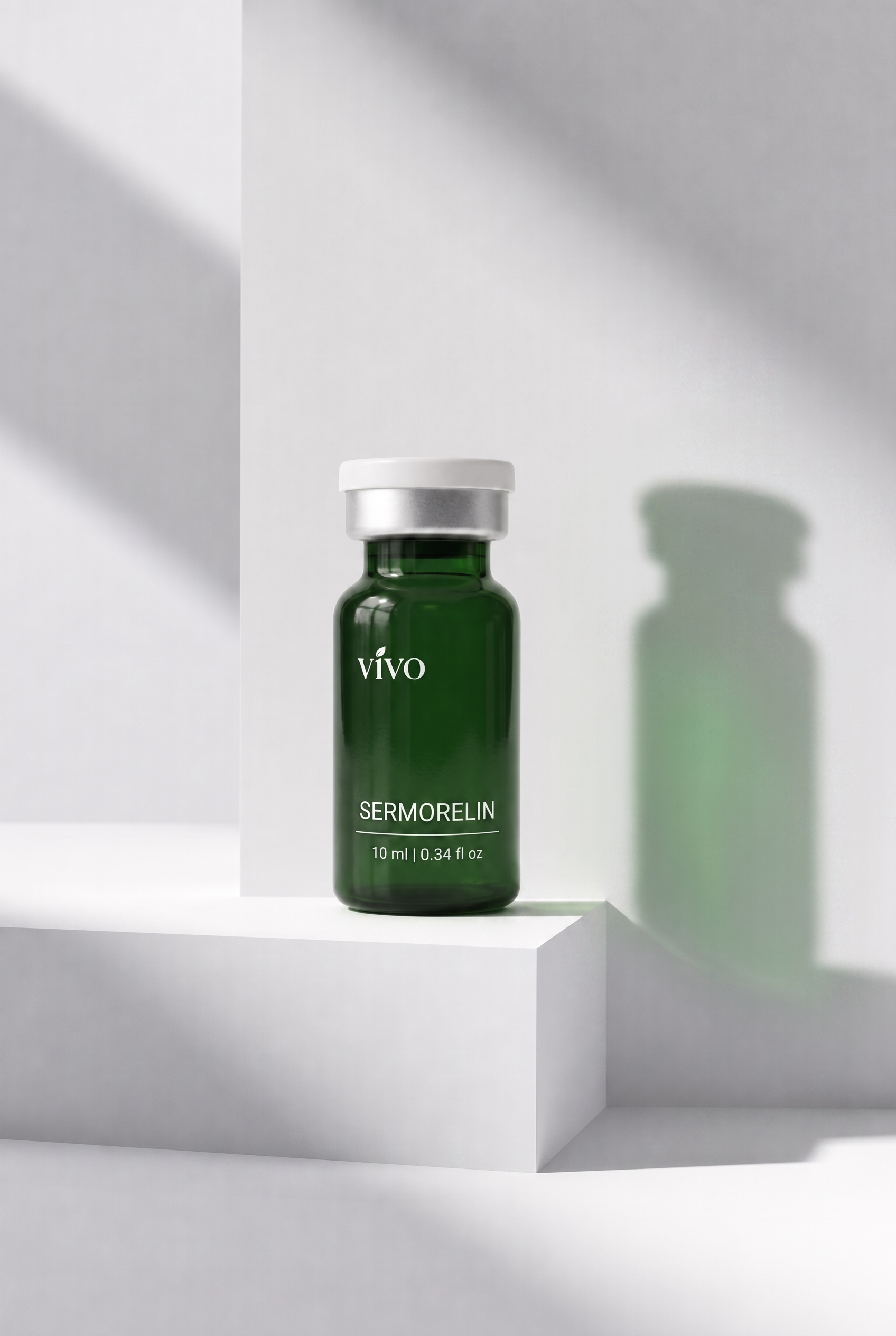 Vivo Sermorelin — forest green glass vial on a white architectural pedestal with soft diagonal light