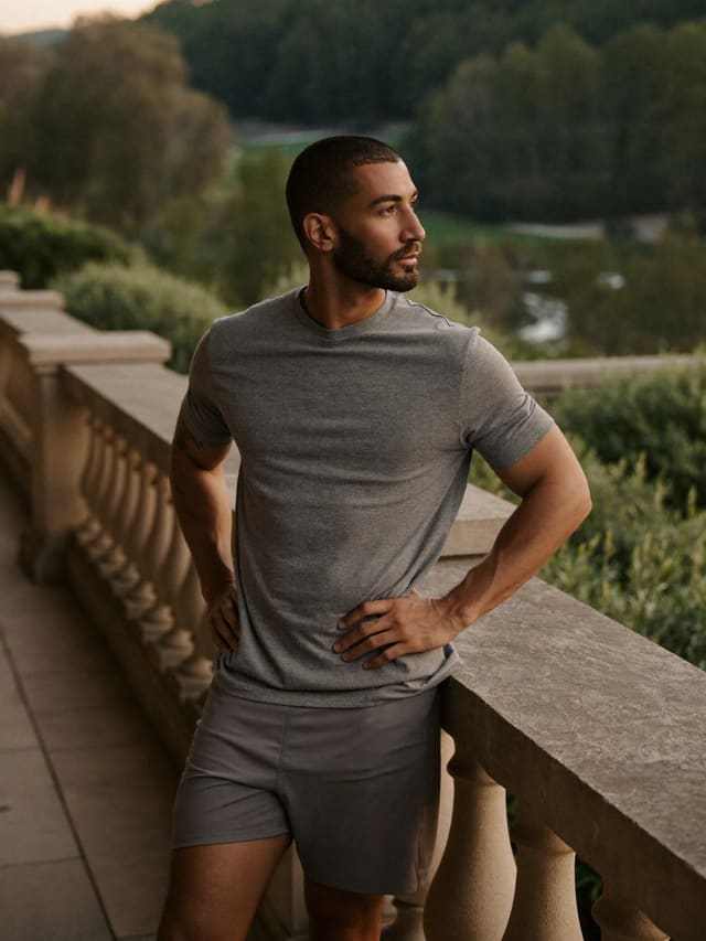 Model in a grey T-shirt on a balustraded terrace overlooking trees